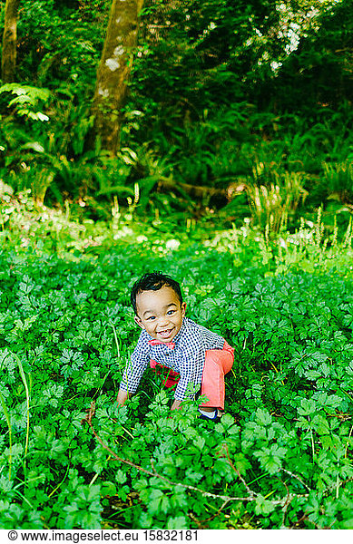 Straight on portrait of a baby boy playing in the grass outdoors