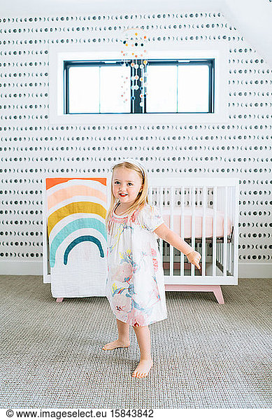 Straight on portrait of a toddler girl dancing in a modern nursery