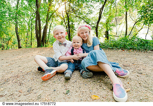 Straight on portrait of three siblings sitting together