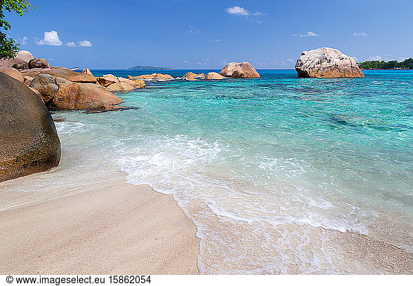 Strand mit blauem Wasser und blauem Himmel und einigen Felsen