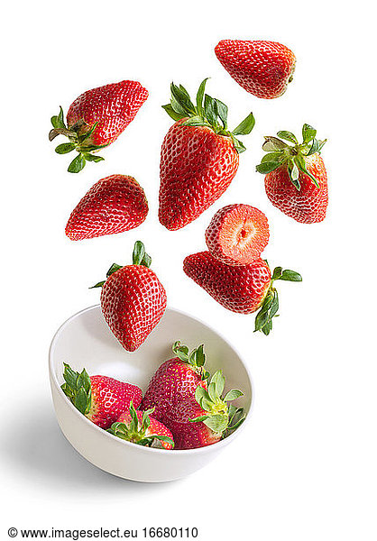 Strawberries flying in white bowl isolated from the background