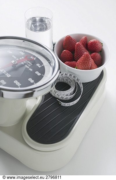Strawberries  glass of water and tape measure on scales