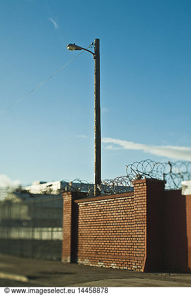 Street Lamp Behind Brick Wall With Concertina Wire