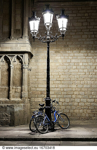 Street lamp illuminated bycicles at night in Barcelona Gothic qu