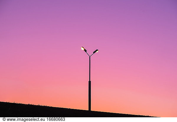 Street lamp post with lights on against vibrant evening sky. Abs
