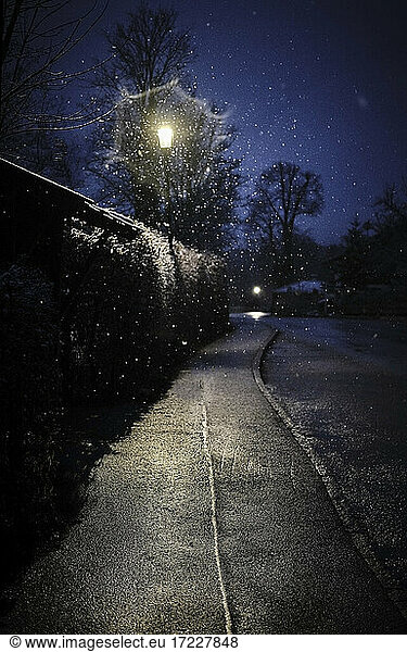 Street light illuminating empty sidewalk at winter night