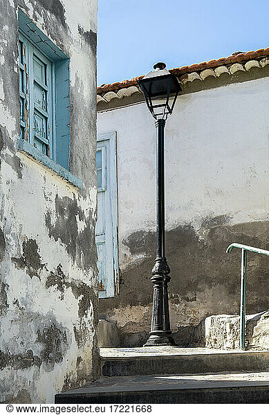 Street light on step amidst houses during sunny day