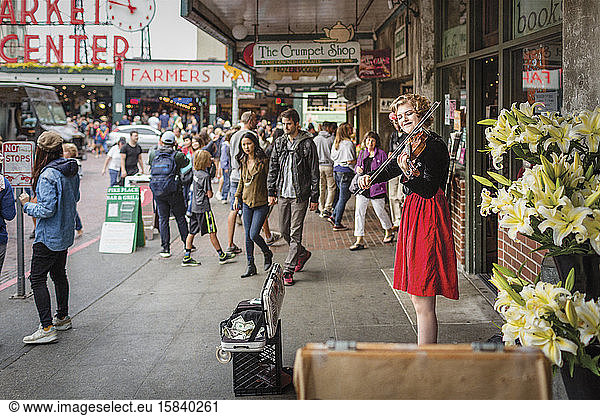 Street musician in red dress plays violin at Pike Place Market