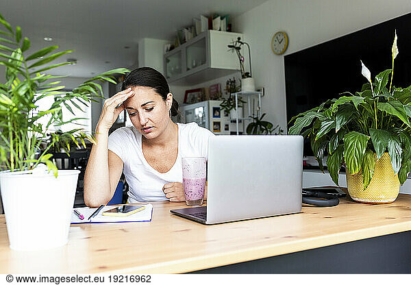 Stressed freelancer using smart phone and sitting at desk