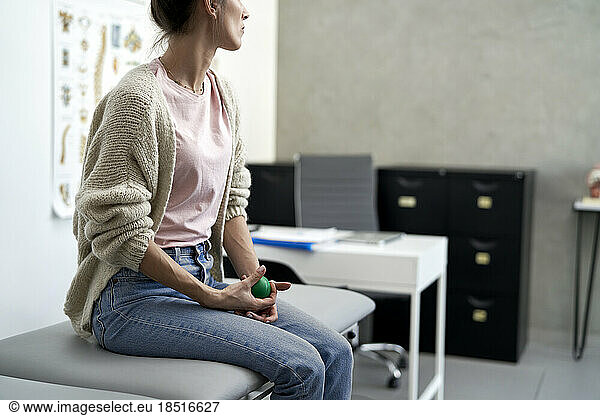 Stressed woman sitting with stress ball on examination table