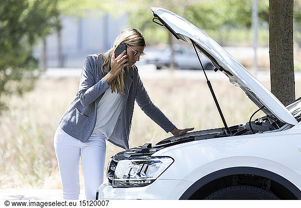 Stressed young woman calling for assistance after breaking down car