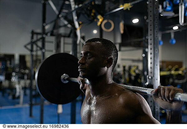 Strong African American man exercising with barbell