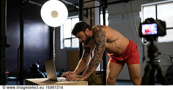 Strong athlete typing on laptop keyboard before webinar