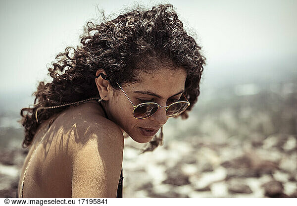Strong attractive young Mexican woman with curly hair and sun glasses