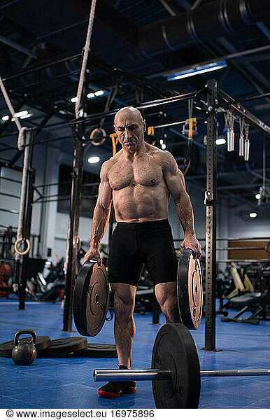 Strong elderly athlete with barbell weight plates