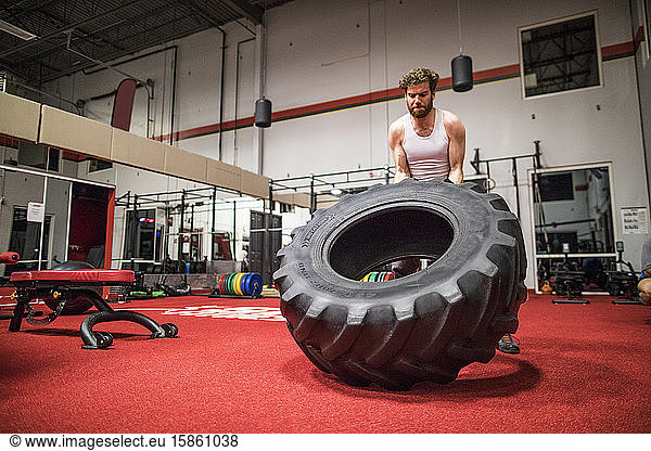 Strong man flipping large tire at the gym.
