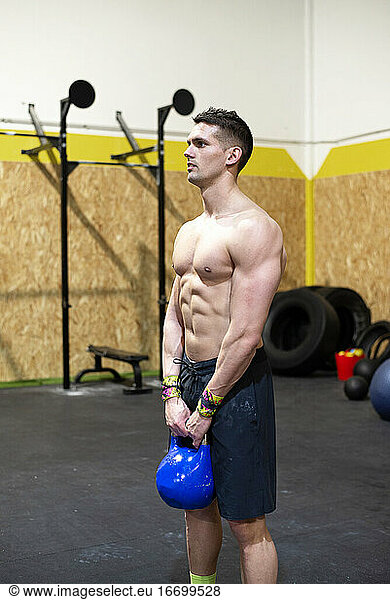 Strong man with dumbbell in hands doing strength exercises in the gym