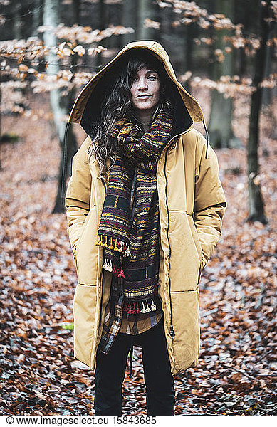 Strong natural woman with curly hair stands empowered in autumn woods