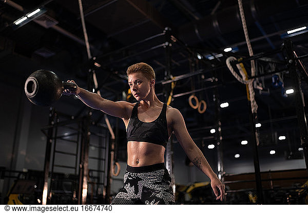 Strong sportswoman exercising with kettlebell