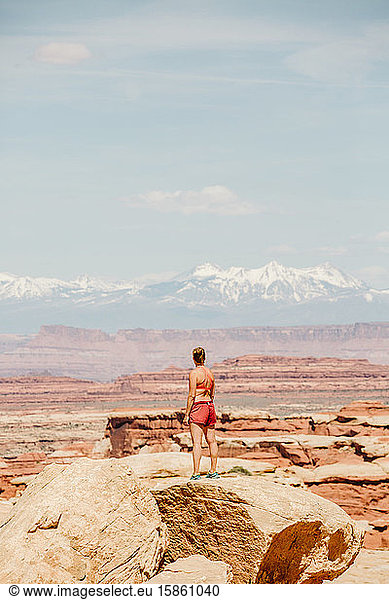 strong tan female hiker looks at la sal mountains in the utah desert