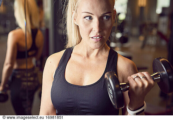 Strong woman with dumbbells training in gym