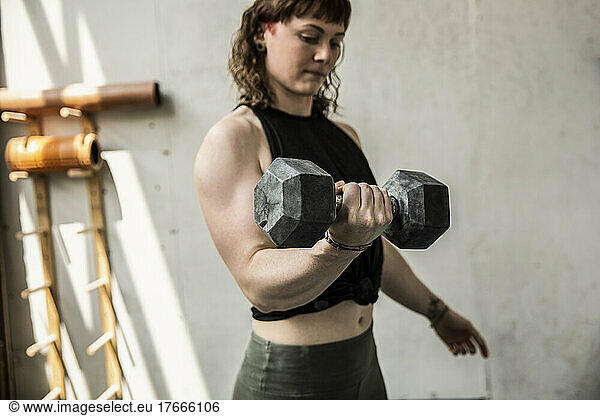 Strong young woman weight training with dumbbell