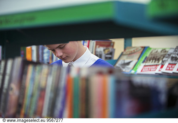 Student in library seen through book shelves