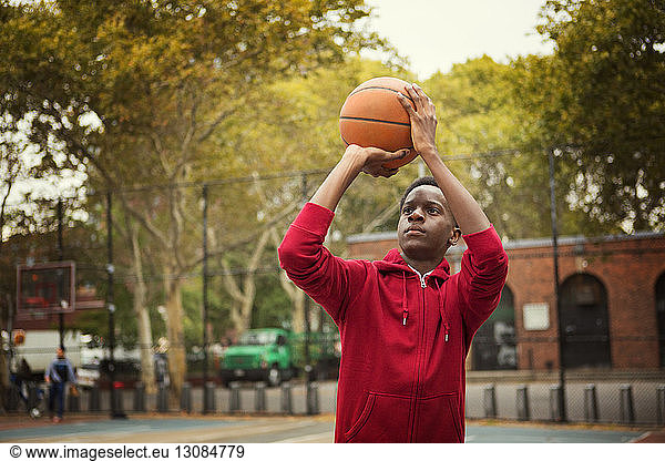 Student taking a shot while playing basketball at court