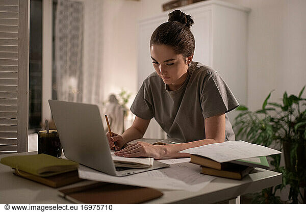 Student taking notes in notebook during studies at home