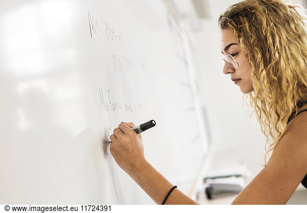 Student (14-15) writing on whiteboard
