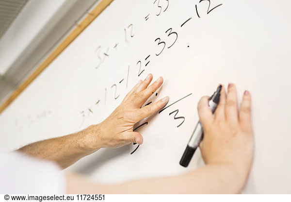 Student (14-15) writing on whiteboard  teacher looking