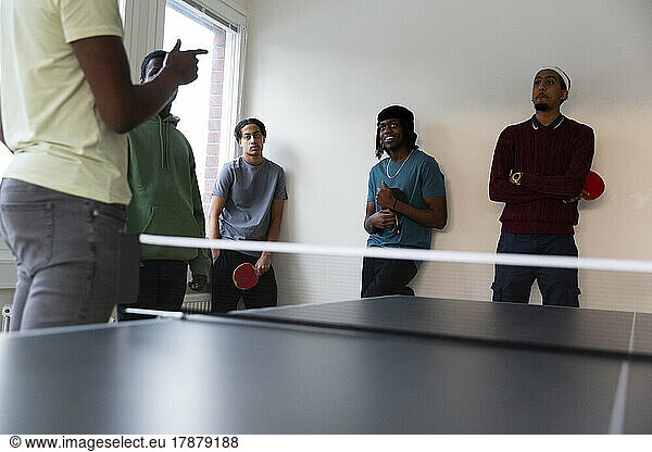 Students attending table tennis training given by instructor in games room