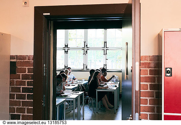 Students learning language in classroom seen through doorway