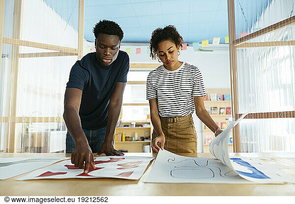 Students looking at art on desk at university