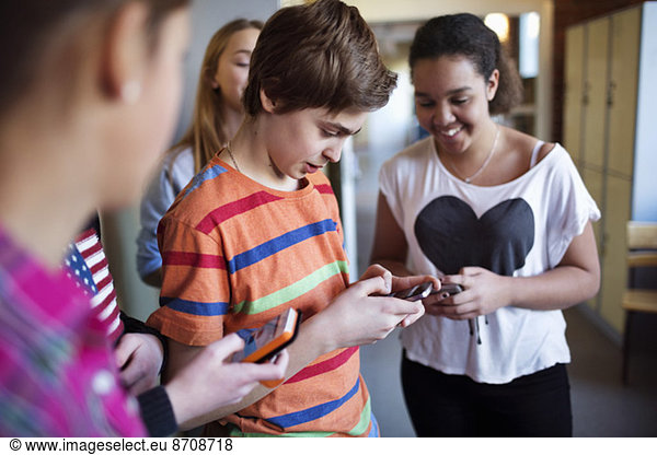 Students using mobile phones in locker room at high school