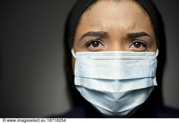 Studio closeup portrait of 21 year old African American woman wearing a medical mask.