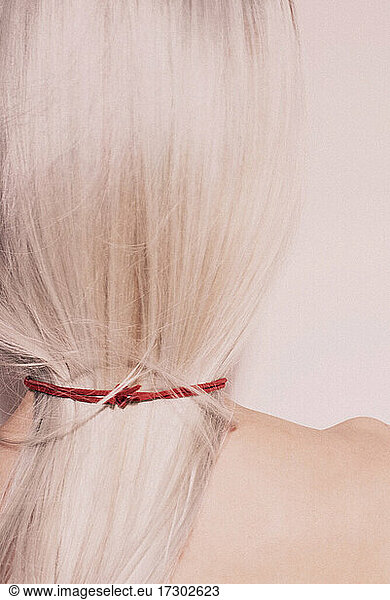 Studio Fashion Portrait Of Blonde Wearing red choker topless. Back view