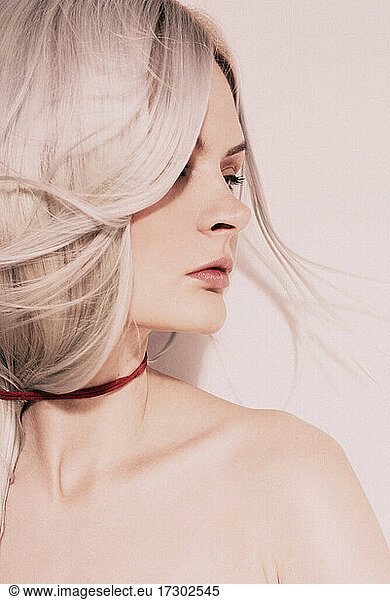 Studio Fashion Portrait Of Blonde Wearing red choker topless  looking aside