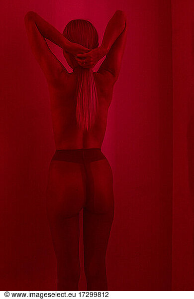 Studio Fashion Portrait Of Blonde Wearing tights  back view  red filter.