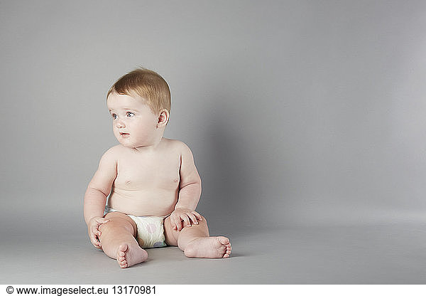 Studio portrait of curious baby girl sitting up