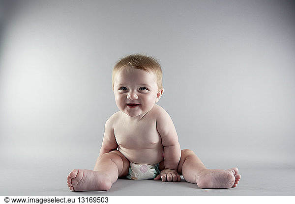 Studio portrait of smiling baby girl sitting up