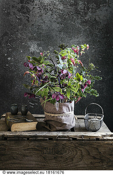 Studio shot of arrangement of springtime flowers in sack standing on wooden crate