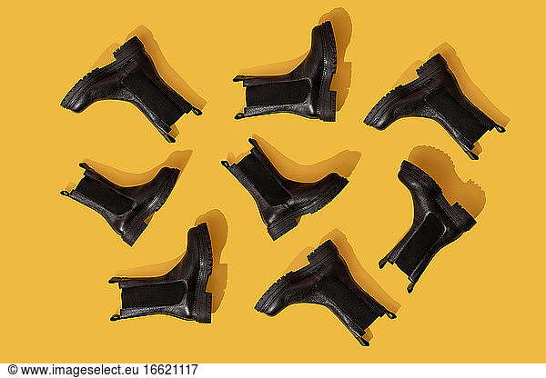 Studio shot of black leather boots against yellow background