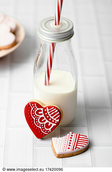 Studio shot of bottle of milk and two heart shaped cookies