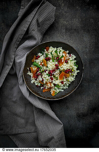 Studio shot of bowl of cauliflower salad with apricot  pomegranate seeds  pistachios  mint and parsley