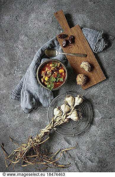 Studio shot of bowl of ready-to-eat North African stew with pumpkin  chickpeas  lentils  dates  cilantro and garlic