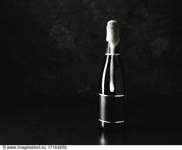 Studio shot of champagne spilling out of black bottle