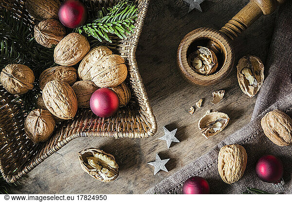 Studio shot of cutting board  star shaped wicker basket  Christmas ornaments  walnuts and simple nutcracker