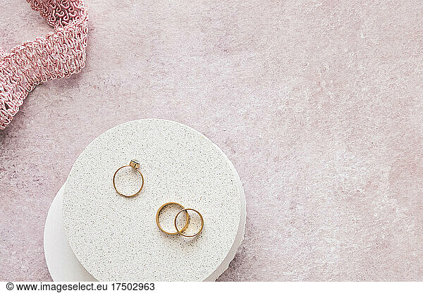 Studio shot of engagement ring and pair of wedding rings against pink background