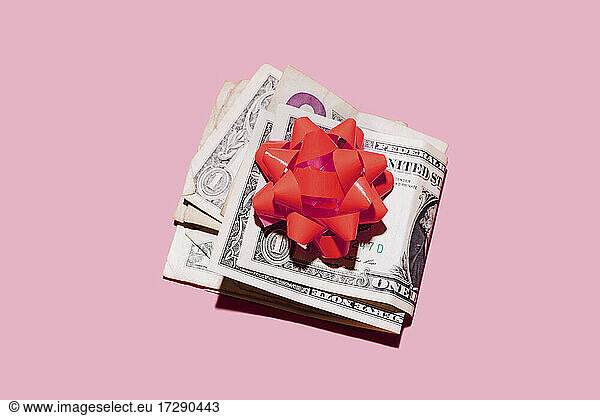 Studio shot of folded dollar bills with red gift bow